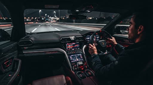 Motion-blurred luxury car interior at night with a glowing red dashboard